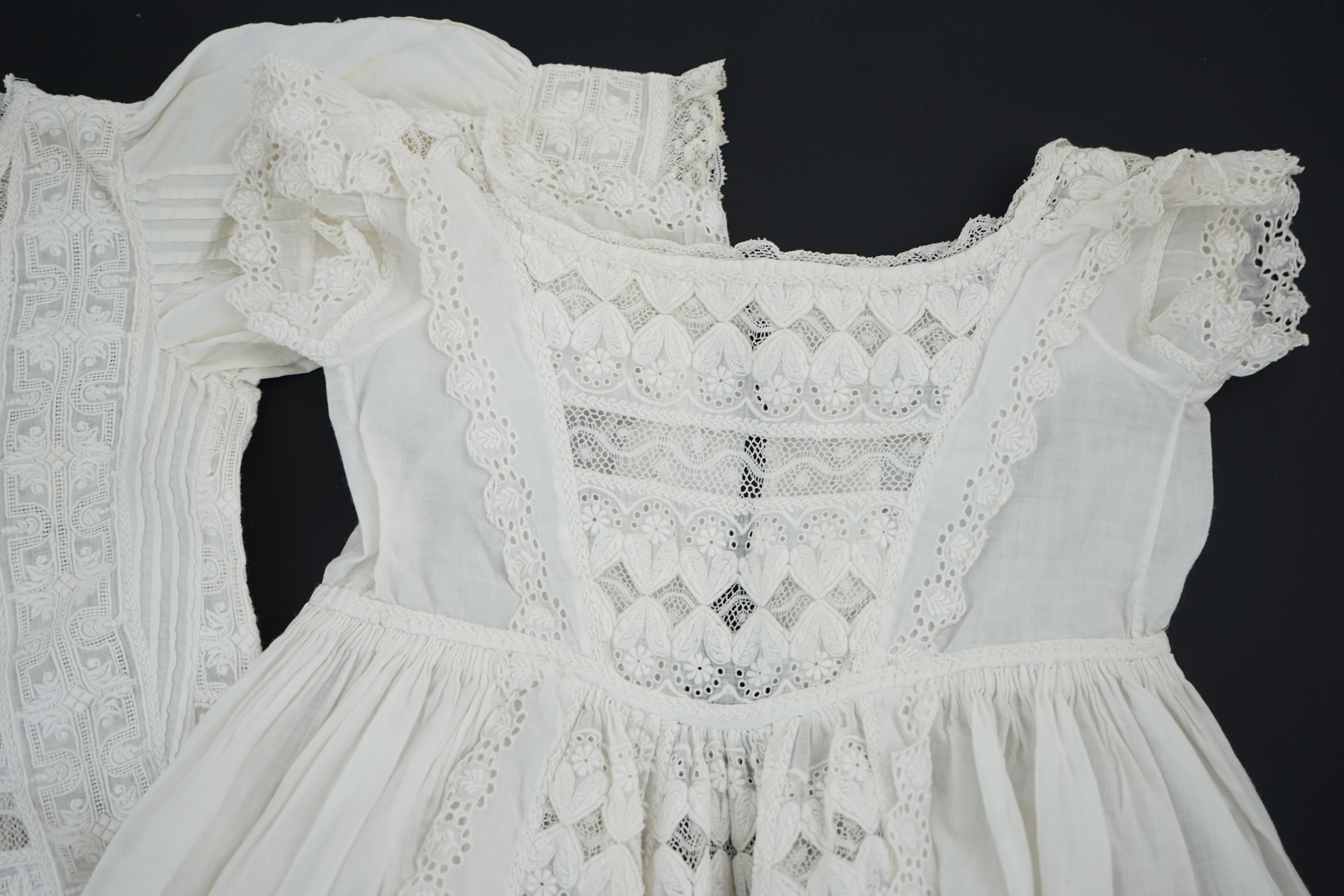 Two unusual 19th century intricately white worked children’s dresses, one hand worked with fine panels of white work, feather stitching and tucking, edged and inserted with hand made Valenciennes lace, the other worked i